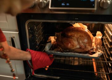 A woman roasting a turkey using leftover marinade.