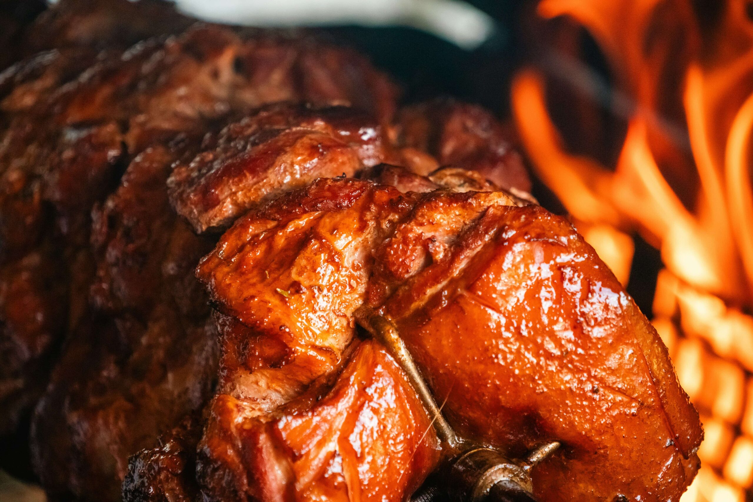A large pork shoulder on the grill with flames