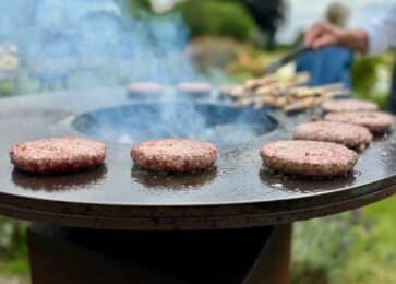 Burger patties cooking on a round flat top griddle