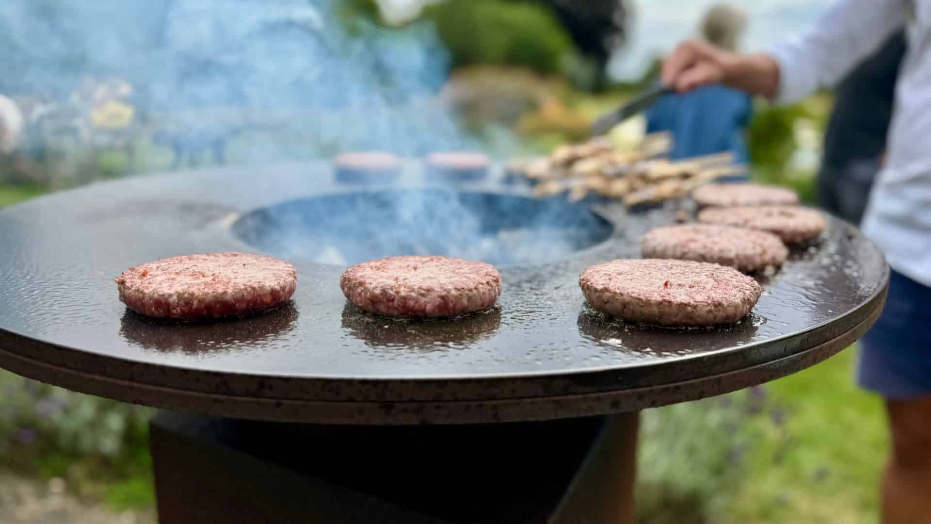 Burger patties cooking on a round flat top griddle