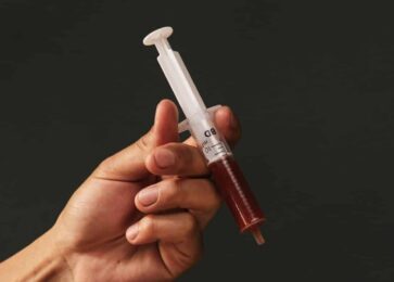 Hand holding a marinade injector filled with marinade